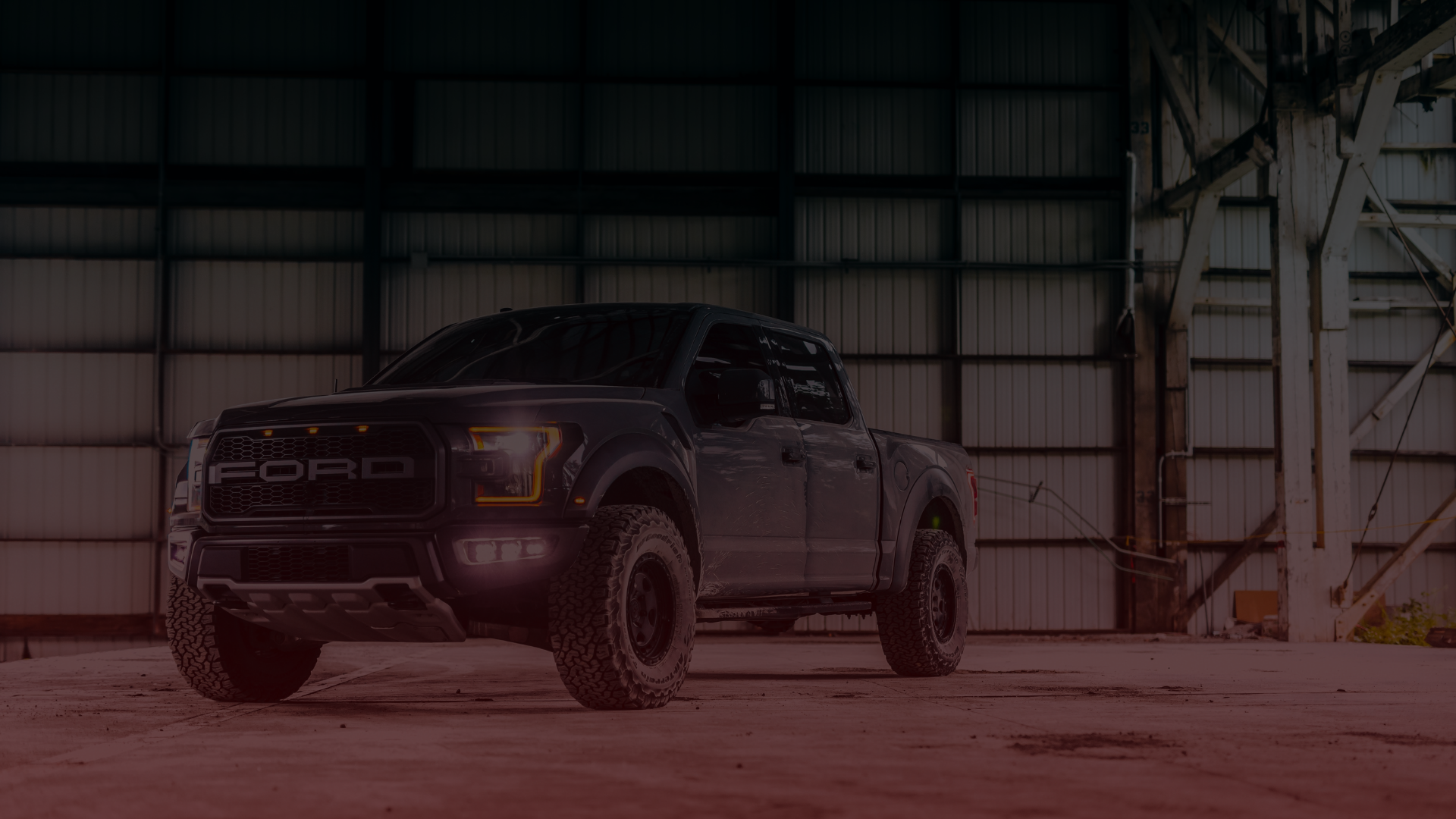 A gray Ford pickup truck, awaiting its repair session in Mississauga, is parked inside an industrial warehouse. Its headlights and front grille are prominently visible as daylight streams through the large windows, highlighting the high ceilings and metal beams. Euro Mechanic | Bloor West Auto Repair Mechanics | Top Reviewed Auto Repair Shop in Mississauga | Visit bloorwestauto.ca