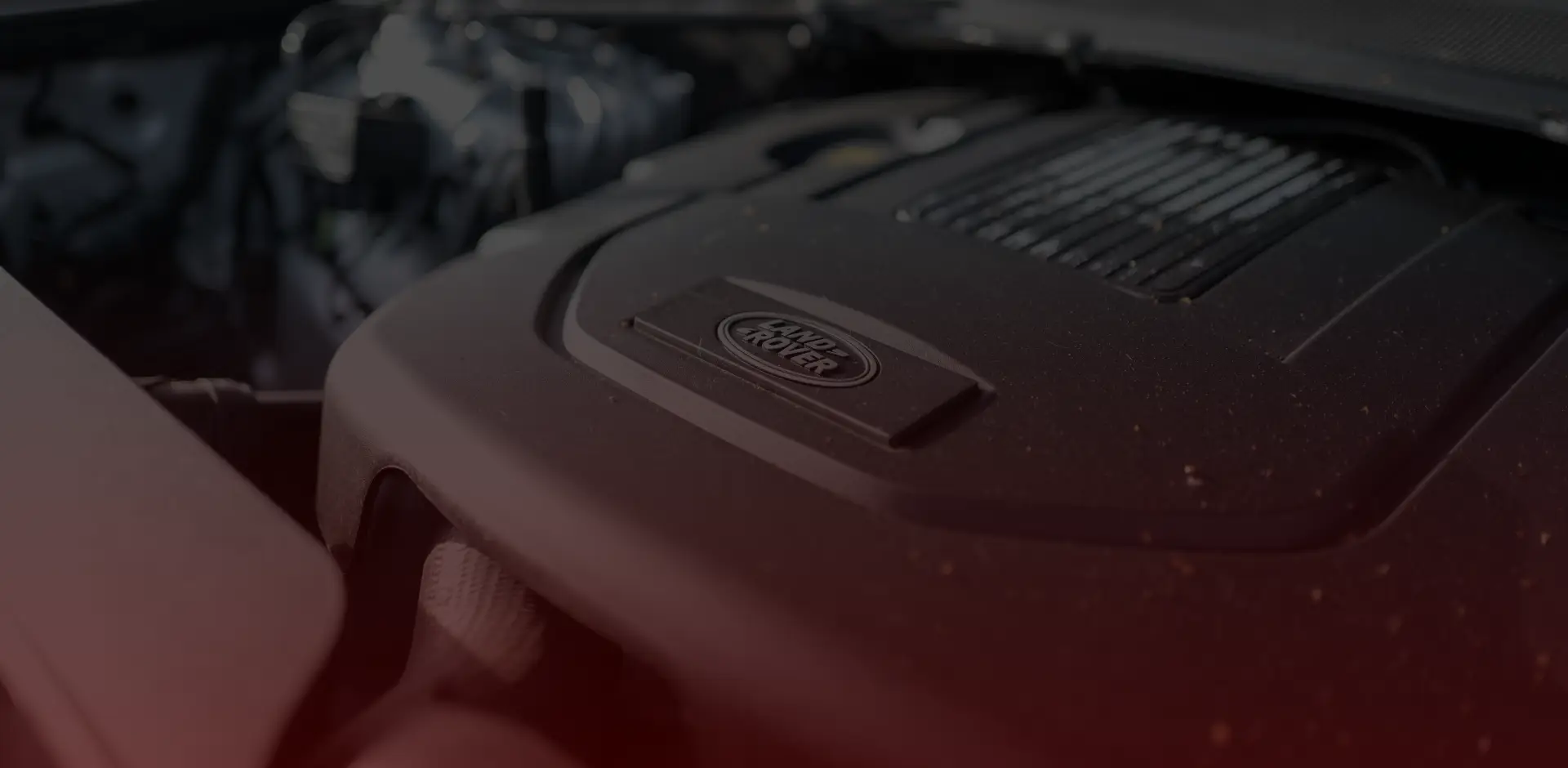 Close-up of a car engine with a focus on the Land Rover logo on the cover, expertly maintained by Bloor West Auto. The engine components are mostly in shades of black and gray, with the background slightly blurred. Euro Mechanic | Bloor West Auto Repair Mechanics | Top Reviewed Auto Repair Shop in Mississauga | Visit bloorwestauto.ca
