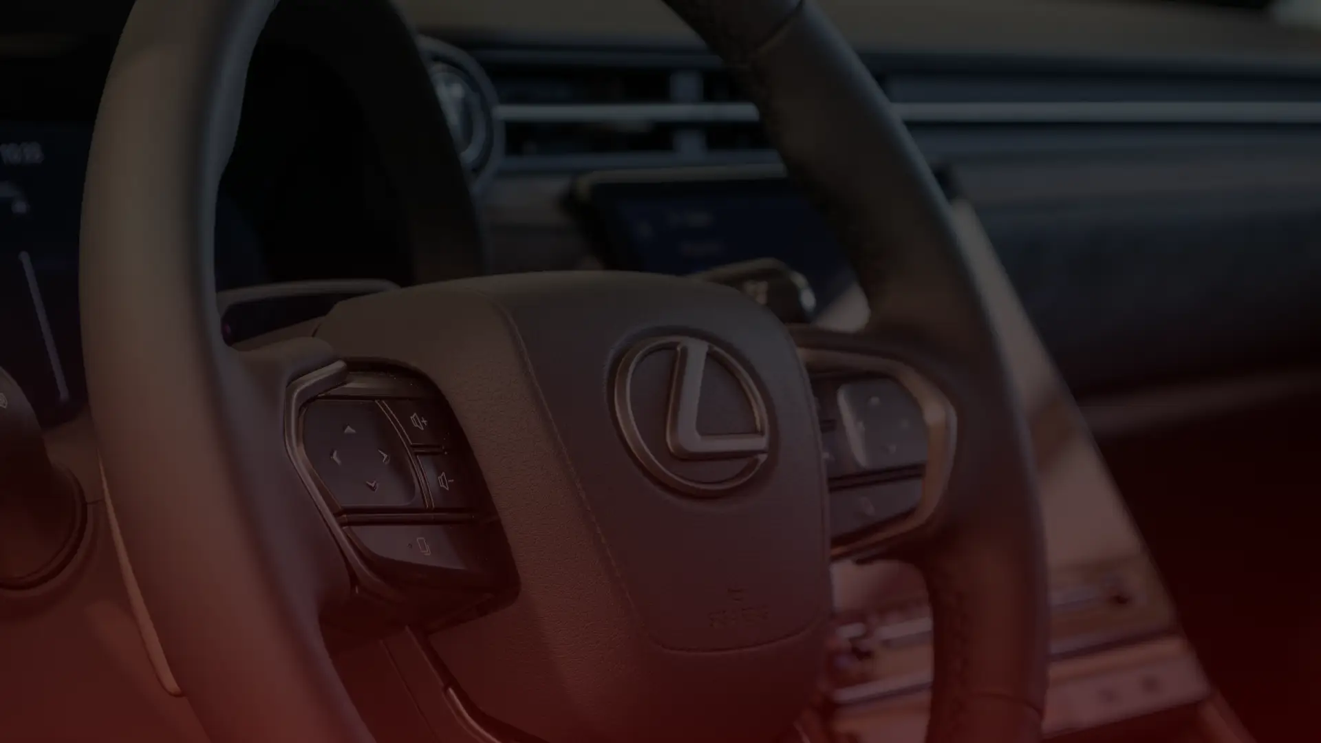 Close-up of a cars steering wheel featuring the Lexus logo. The stylish interior includes buttons on the wheel for controls, similar to those seen in top repair shops across Mississauga. The modern dashboard and console are dimly lit with a reddish tint. Euro Mechanic | Bloor West Auto Repair Mechanics | Top Reviewed Auto Repair Shop in Mississauga | Visit bloorwestauto.ca