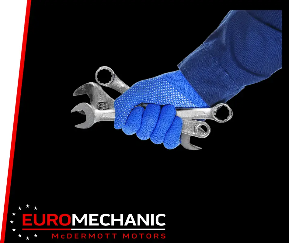 A hand in a blue glove holds several metal wrenches against a black background, highlighting the skilled craftsmanship of EuroMechanic McDermott Motors. Car Repair Mississauga is displayed at the bottom in bold white and red text. Euro Mechanic | Bloor West Auto Repair Mechanics | Top Reviewed Auto Repair Shop in Mississauga | Visit bloorwestauto.ca