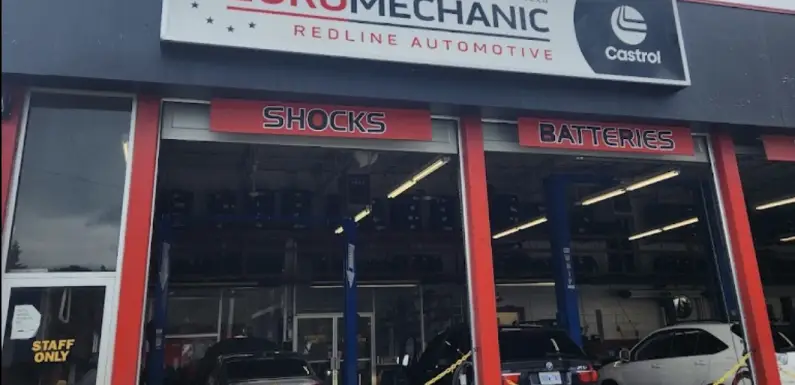 A car repair shop, Bloor West Auto, features a sign reading Euro Mechanic Redline Automotive and Castrol above three service bays. Inside, signs for Shocks and Batteries are visible, along with several parked cars. A discreet Staff Only door is on the left. Euro Mechanic | Bloor West Auto Repair Mechanics | Top Reviewed Auto Repair Shop in Mississauga | Visit bloorwestauto.ca