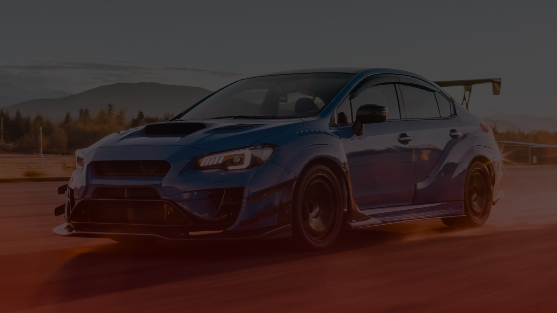 A blue sports car with a large rear spoiler cruises down the road at sunset, reminiscent of the thrilling drives youd expect from a Subaru. The distant mountains and clear sky frame the scene, while the sun casts an orange glow that could make any mechanic in Mississauga proud. Euro Mechanic | Bloor West Auto Repair Mechanics | Top Reviewed Auto Repair Shop in Mississauga | Visit bloorwestauto.ca