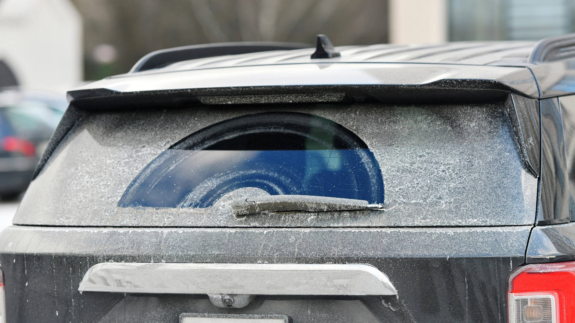 A car’s rear window is mostly covered in frost except for a clean semicircle where the rear wiper has swept, revealing the glass beneath. The vehicle is parked outdoors on a cold day. EuroMechanic - Bloor West Auto | Top Reviewed Auto Repair Shop in Mississauga | Visit EuroMechanic - Bloor West Auto