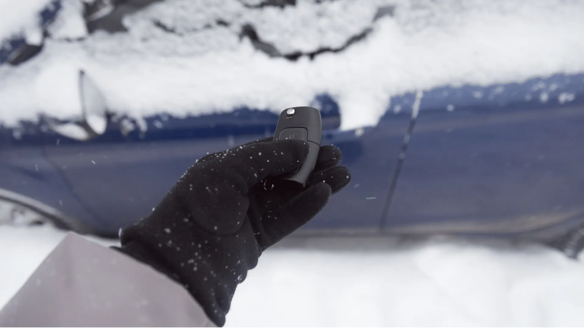 A person wearing a black glove holds a car key fob near a snow-covered blue car, with snowflakes visible on the glove and the ground. EuroMechanic - Bloor West Auto | Top Reviewed Auto Repair Shop in Mississauga | Visit EuroMechanic - Bloor West Auto